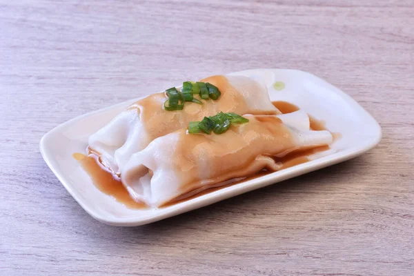Steamed rice rolls with fresh prawn filling served in a dish  on wooden table