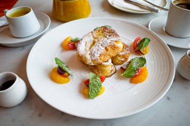 Akçaağaç şuruplu Fransız tostu, ahududu sosu ve beyaz tabakta meyveler..