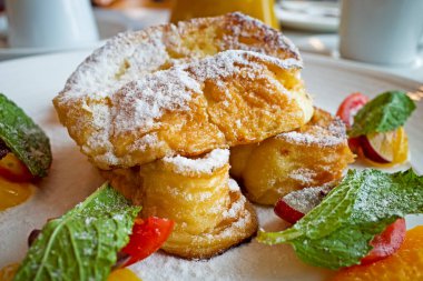 Akçaağaç şuruplu Fransız tostu, ahududu sosu ve beyaz tabakta meyveler..