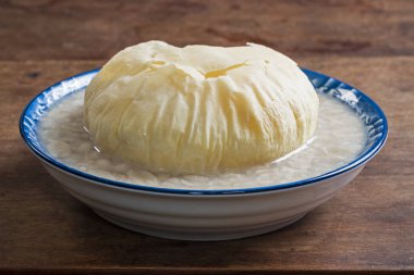 Kahverengi şekerli çörekli tatlı fıstık çorbası ahşap masada bir kasede  