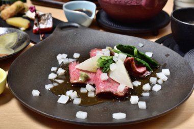 Siyah tabakta taze sebzeli kurutulmuş et salatası. İnce dilimlenmiş saşimi tarzı..