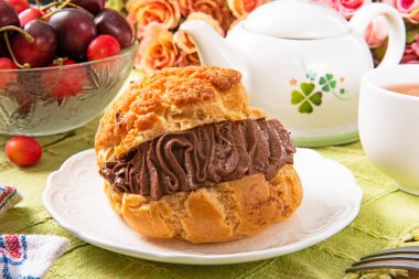 Beyaz tabakta çikolata kremalı profiterol. .  