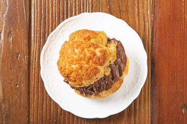 Beyaz tabakta çikolata kremalı profiterol. .  