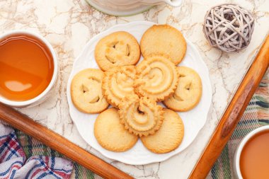 Tahta tepside çay ve beyaz tabakta Danimarka usulü kurabiye..