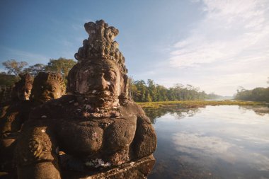 Angkor Thom Tapınağı 'na giden yolda manzaraya karşı heykellerin yüzleri. Kamboçya 'da Siem Reap yakınlarında ünlü bir seyahat merkezi.