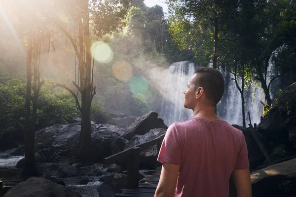 男は熱帯雨林の中を歩く山の中で高い滝 カンボジアで熱帯雨林を楽しむ観光客 — ストック写真