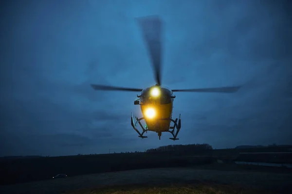 Flying helicopter of emergency medical service during take off from meadow at dusk. Themes rescue, help and hope
