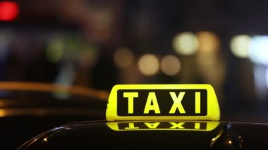 Selective focus on taxi sign on roof of car against busy city street at night. Real time in 4K resolution.