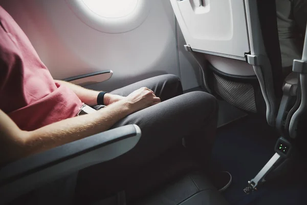 Man resting during flight. Legroom between seats in commercial airplane.