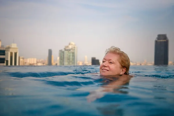 Aktive Seniorin Schwimmt Pool Mit Blick Auf Moderne Stadt — Stockfoto