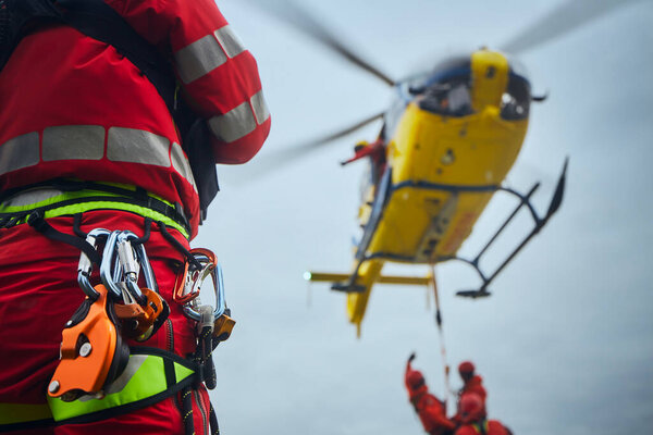 Selective focus on safety harness of paramedic of emergency service in front of helicopter. Themes rescue, help and hope