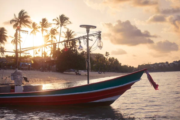 美しい夕日でヤシの木と牧歌的な砂浜の近くの小さな木製のボート タイのサムイ島 — ストック写真