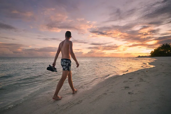 Widok Człowieka Strojach Kąpielowych Trzymającego Japonki Ręku Chodzącego Boso Samotnie — Zdjęcie stockowe