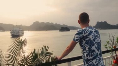 Yolcu gemisinin adalar arasında yelken açmasından zevk alan bir adam. Denizde karst oluşumları olan popüler turizm merkezi, Vietnam 'da Ha Long Körfezi.