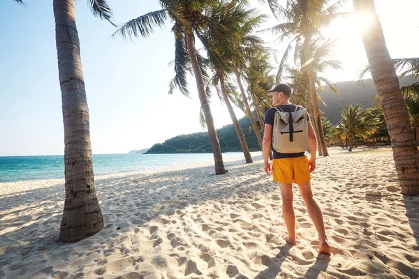 ヤシの木と美しい砂のビーチを歩くと日没を見てバックパックを持つ観光客のリアビュー ベトナムのチャム諸島 — ストック写真