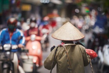 Hanoi, Vietnam 'daki Old Quarter' da trafik motosikletlerine karşı yürüyen kişinin geleneksel konik şapkasına odaklanın.