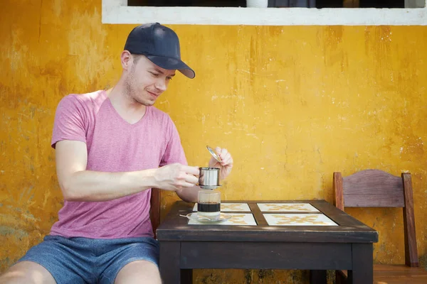 男は凝縮ミルクと伝統的なホットベトナムコーヒーのガラスを楽しんで ベトナムの旅行者 — ストック写真