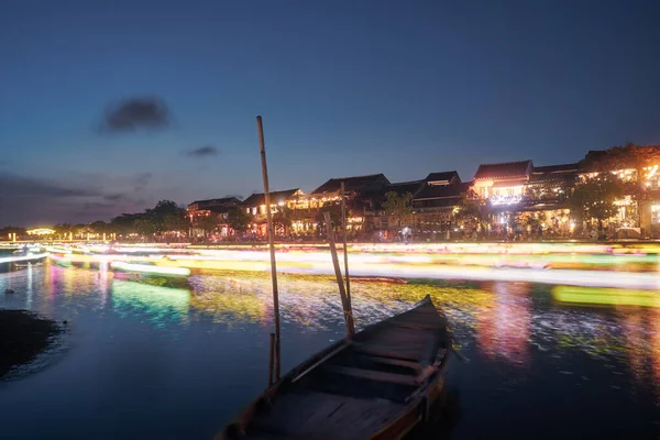 動きに伝統的なランタン付きのボートのライトトレイル ベトナムの古代都市ホイアンの水運河とウォーターフロントの夜のシーン — ストック写真