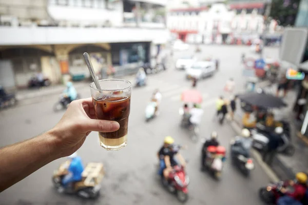 手里拿着一杯含有浓缩牛奶的越南冰镇咖啡 在越南河内老城区的繁忙街道上喝咖啡的男人 — 图库照片