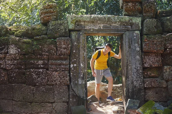 男は古い遺跡を歩いて ジャングルの真ん中にある神秘的な古代の寺院に来ています カンボジアの旅行者 — ストック写真