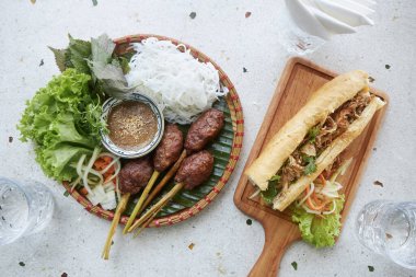 Vietnam 'ın tadı. Lokantadaki geleneksel Vietnam yemekleri. Domuz köftesi, erişte, salata ve Banh mi sandviçi.