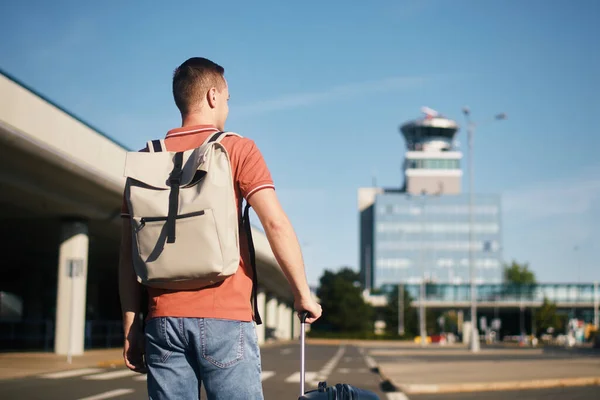 飛行機で旅行する 旅行者は空港ターミナルまで歩いています 航空交通管制塔に対するスーツケースを持つ男 — ストック写真