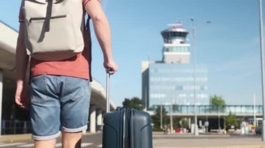 Uçakla seyahat et. Gezgin havaalanı terminaline gidiyor. Bavullu adam hava trafik kontrol kulesine karşı. 4K çözünürlükte gerçek zamanlı.