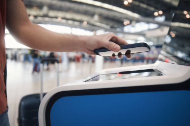 Öz servis kayıt makinesini kullanırken adamın eli. Havaalanı terminalindeki akıllı telefondan yolcu tarama bileti.