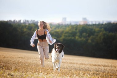 Mutlu genç kız köpeğiyle birlikte şehir manzarasına karşı koşuyor. Çek Dağ Köpeği ile neşeli hayvan sahibi