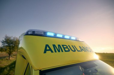 Günbatımında gökyüzüne karşı acil tıbbi servisin sirenleri. Ambulans arabasının çatısında teşhirci. Tema kurtarma, acil durum ve sağlık hizmetleri.