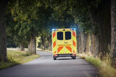 Country Road 'da acil serviste çalışan sarı ambulans arabası. Tema kurtarma, acil durum ve sağlık hizmetleri.
