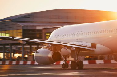 Havaalanındaki uçak. Güzel gün doğumunda yolcu uçağı terminal binasına doğru hareket ediyor.