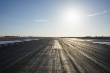 Açık gökyüzüne karşı yön işaretli uzun havaalanı pistinin yüzey seviyesi.