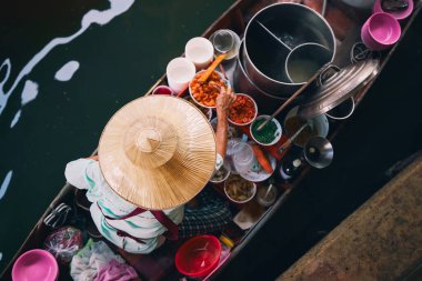 Yüzen piyasadaki geleneksel satıcı şapkasına odaklan. Kadın, Bangkok, Tayland yakınlarındaki Damnoen Saduak 'ta su üzerinde yemek hazırlıyor.