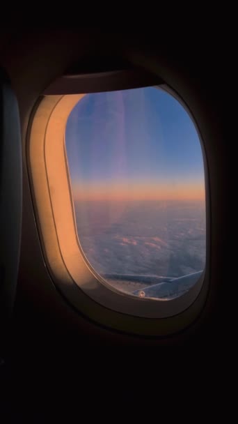 息をのむような夕日で雲の上を飛行中の飛行機窓から眺める — ストック動画