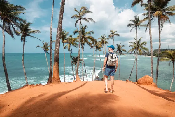 Podróżnik Plecakiem Spacerujący Wśród Palm Kokosowych Wzgórzu Przed Tropikalną Plażą Zdjęcie Stockowe