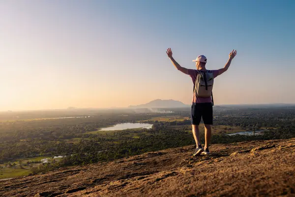 背负背包享受日落的后视镜 在斯里兰卡举手投足的快乐个人旅行者 图库照片