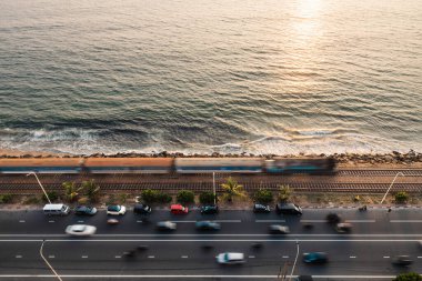 Hint Okyanusu 'nun üzerinde gün batımında sahil boyunca yol ve tren yolu. Tren Colombo, Sri Lanka 'ya varıyor.