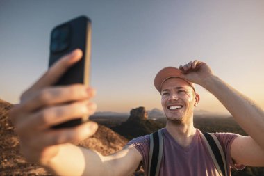 Mutlu adam yaz tatili gününden fotoğraf çekiyor. Yakışıklı turist şapkalı ve kameraya gülümsüyor Sri Lanka 'da Sigirya kayası olan tropik manzaraya karşı.