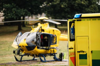 Selective focus on blue light flasher on ambulance car of emergency medical service against helicopter. Themes rescue, urgency and health care clipart