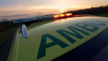 Gün batımında ambulans servisinin çatısındaki kırmızı ve mavi ışıkların yakın çekimi. Sağlık hizmetleri, kurtarma, kazalar ve felaketler.