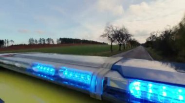 Ambulans arabasının çatısındaki kırmızı ve mavi ışıkların yakın çekimleri yolda. Sağlık hizmetleri, kurtarma, kazalar ve felaketler.