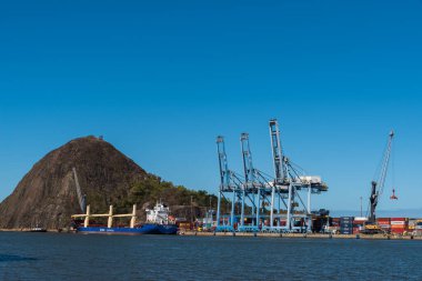 Vitoria, Brazil - August 14, 2022: Cargo cranes and transport ship at the harbor of Espirito Santo state capital city. clipart