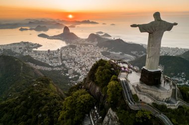 Rio de Janeiro, Brezilya - 21 Mart 2023: Kurtarıcı İsa Corcovado Dağı 'nın tepesinde gün doğumunda ufuk çizgisinde Şekerleme Dağı ile birlikte.