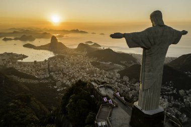 Rio de Janeiro, Brezilya - 21 Mart 2023: Kurtarıcı İsa Corcovado Dağı 'nın tepesinde gün doğumunda ufuk çizgisinde Şekerleme Dağı ile birlikte.