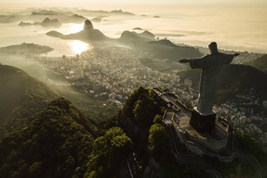 Rio de Janeiro, Brezilya - 21 Mart 2023: Kurtarıcı İsa Corcovado Dağı 'nın tepesinde gün doğumunda ufuk çizgisinde Şekerleme Dağı ile birlikte.