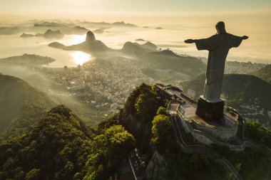 Rio de Janeiro, Brezilya - 21 Mart 2023: Kurtarıcı İsa Corcovado Dağı 'nın tepesinde gün doğumunda ufuk çizgisinde Şekerleme Dağı ile birlikte.
