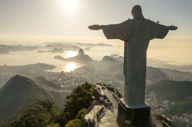 Rio de Janeiro, Brezilya - 21 Mart 2023: Kurtarıcı İsa Corcovado Dağı 'nın tepesinde gün doğumunda ufuk çizgisinde Şekerleme Dağı ile birlikte.