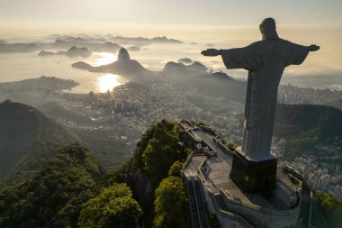 Rio de Janeiro, Brezilya - 21 Mart 2023: Kurtarıcı İsa Corcovado Dağı 'nın tepesinde gün doğumunda ufuk çizgisinde Şekerleme Dağı ile birlikte.