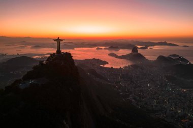 Rio de Janeiro, Brezilya - 10 Haziran 2023: Kurtarıcı İsa Corcovado Dağı 'nın tepesinde gün doğumunda ufuk çizgisinde Şekerleme Dağı ile birlikte.